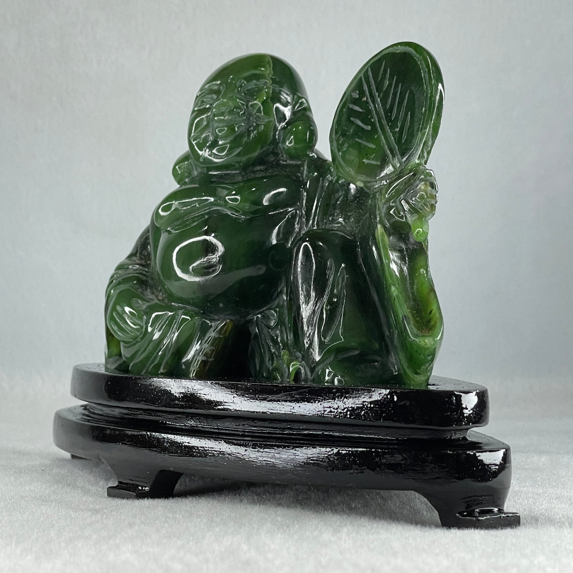 Natural Dark Green Serpentine Siting Milo Buddha with Waving Fan with Wooden Stand Display 765.0g 180.0 by 90.0 by 115.0mm - Huangs Jadeite and Jewelry Pte Ltd