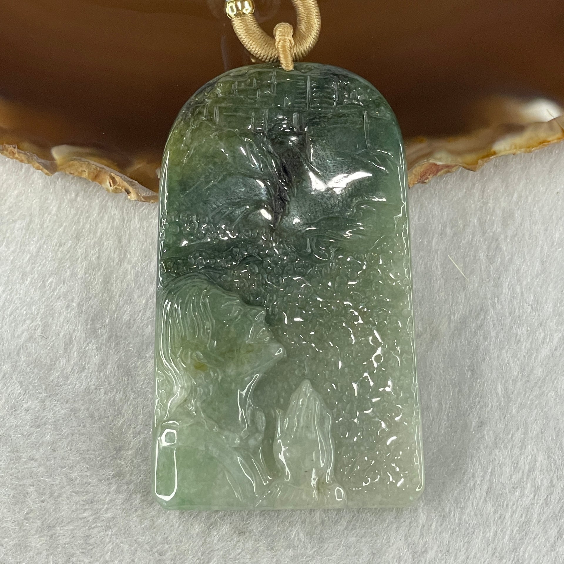 Translucent green jadeite pendant carved with standing figure on white background
