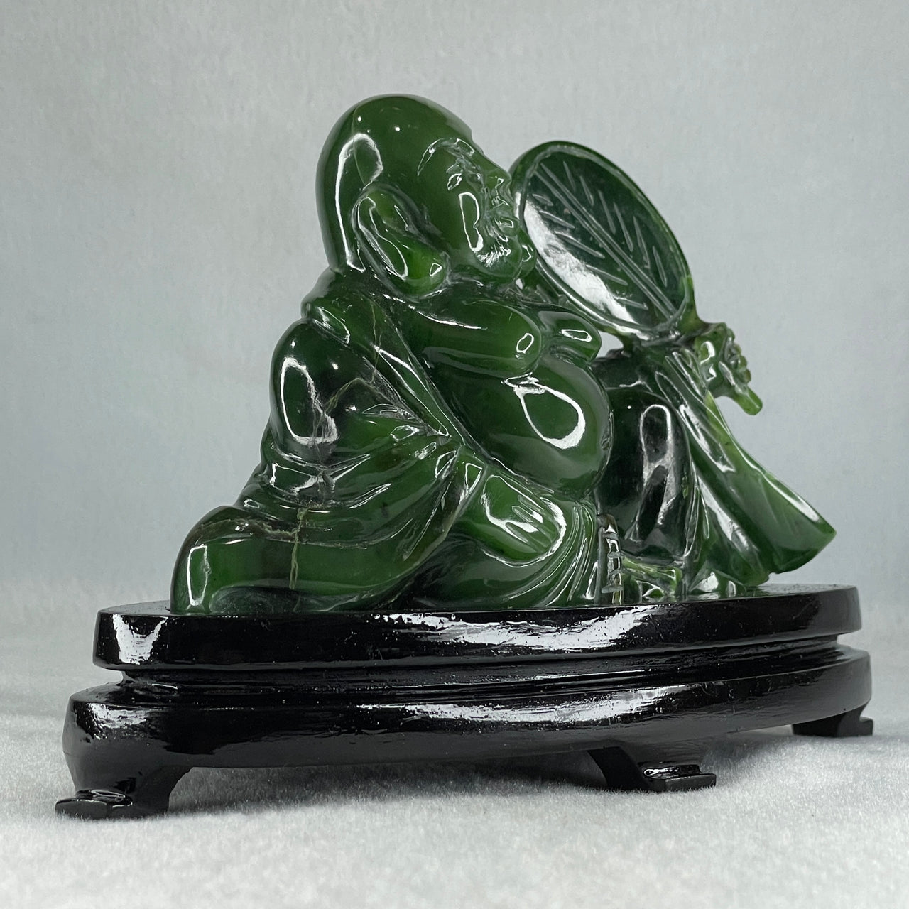 Natural Dark Green Serpentine Siting Milo Buddha with Waving Fan with Wooden Stand Display 765.0g 180.0 by 90.0 by 115.0mm - Huangs Jadeite and Jewelry Pte Ltd