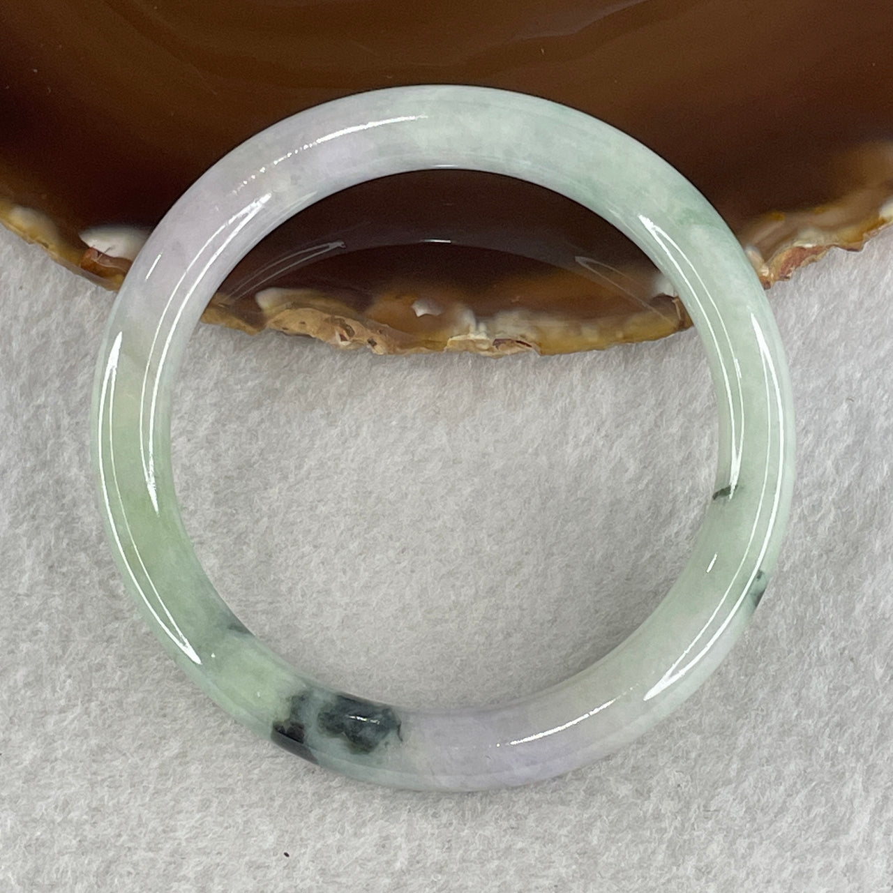 Translucent green and lavender jadeite bangle on a simple display surface