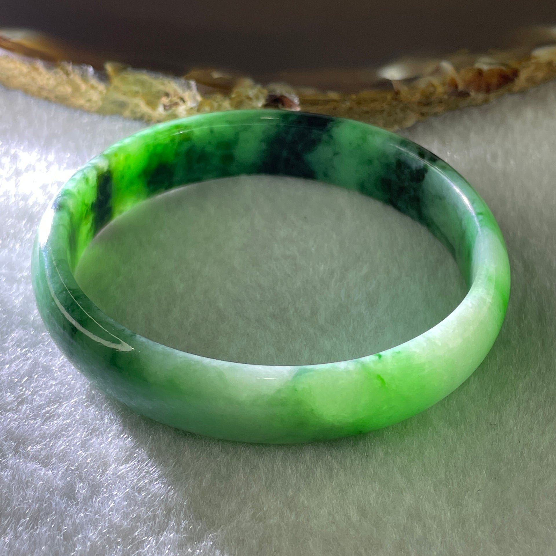Type A Natural Old Mine Spicy Green with Dark Green Piao Hua Flora Jadeite Oval Bangle 26.28g 131.60cts Inner Diameter 52.55mm 46.90 by 5.40mm with NGI Cert 63804952 (Very Very Slight Internal Lines) - Huangs Jadeite and Jewelry Pte Ltd